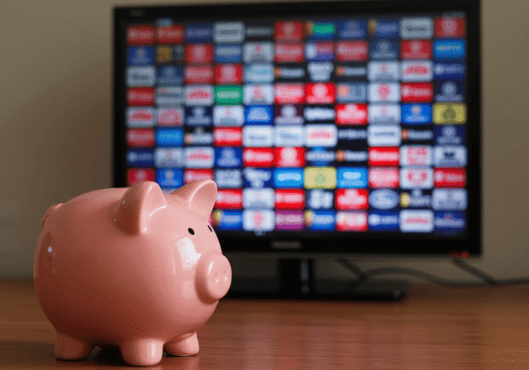 A piggy bank next to a remote, illustrating a cheap IPTV subscription that saves money.